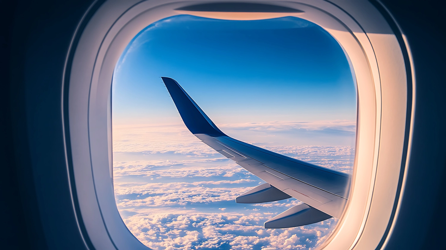 Wonespray UG - Flugzeugfenster mit blauem Himmel und Flügel